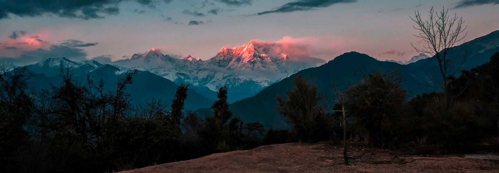 Breathtaking view of snowcapped mountains glowing under a twilight sky with rich cloud formations.